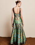 Woman wearing the ALEMAIS sustainable Charlotte Gown, a flowing maxi-length dress featuring intricate floral print details and draped long sleeves.. LUXAMORE