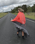 Person sitting on a road wearing estilo emporio dress, under a cloudy sky.
