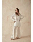 Estilo Emporio Linen Pant Novo Flare - Brasile Natural worn by model in natural setting LUXAMORE
