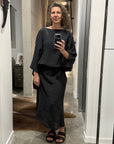 Woman taking a mirror selfie wearing la bottega di brunella linen dress made in italy in a hallway.