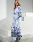 Maxi dress: Miss Goodlife Blue Spirit wrap-neck dress with 3/4 sleeves and tie belt. worn by model in lifestyle shot at home LUXAMORE