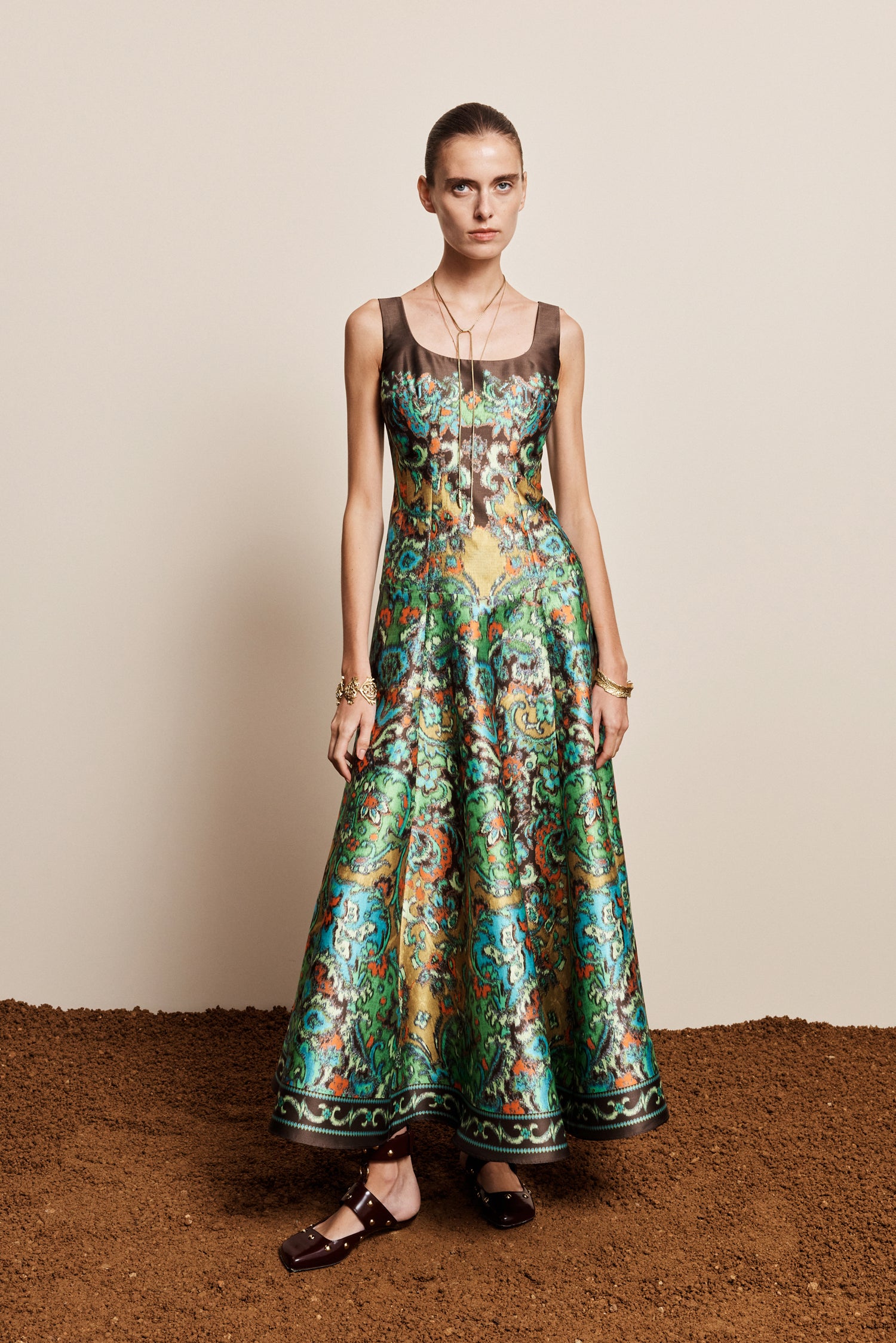 Woman wearing the ALEMAIS sustainable Charlotte Gown, a flowing maxi-length dress featuring intricate floral print details and draped long sleeves.. LUXAMORE