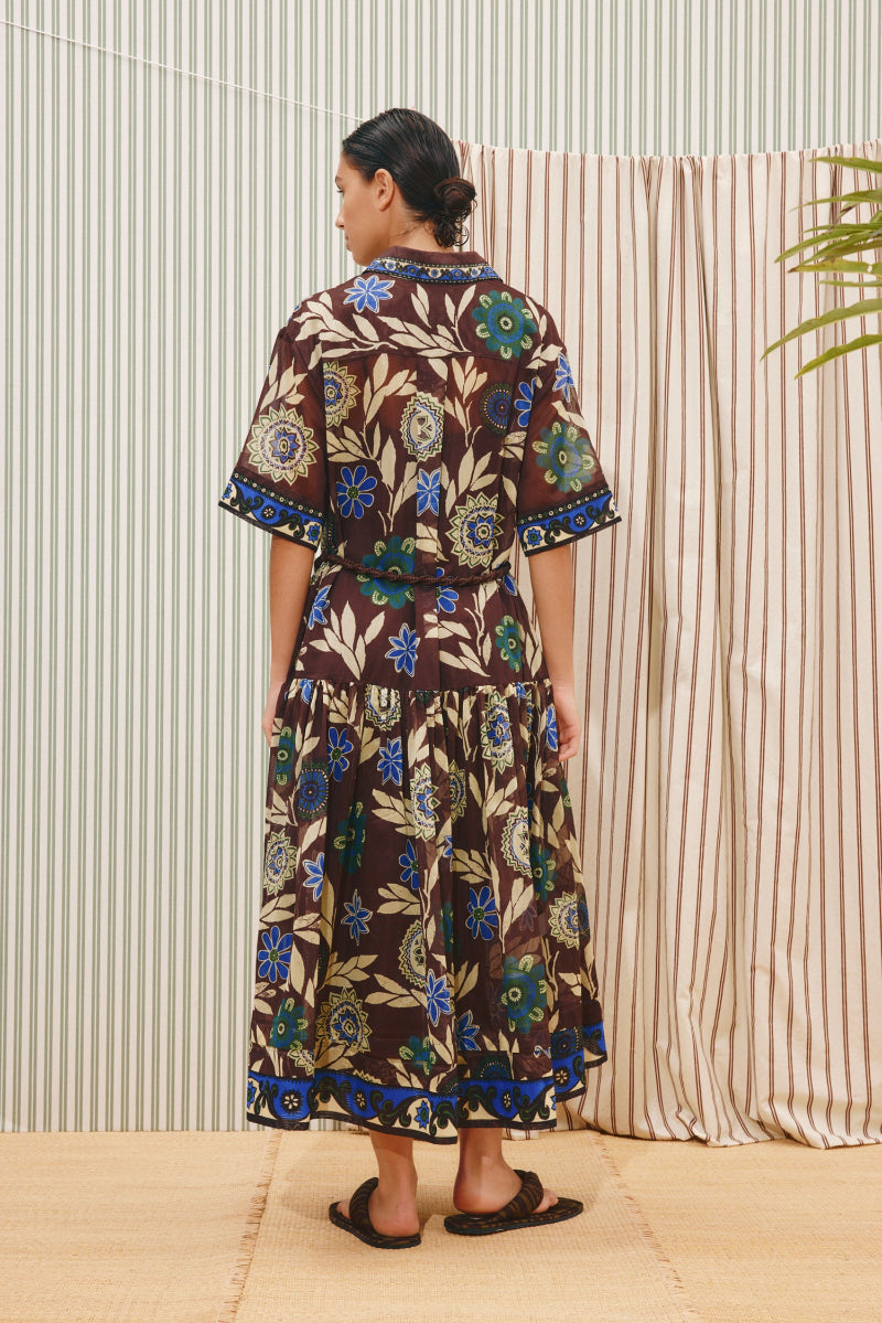 Alemais Jasper Shirtdress Woman wearing a floral dress standing in front of striped curtains