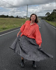 Person standing on a road wearing estilo emporio  with a cloudy sky and fields in the background