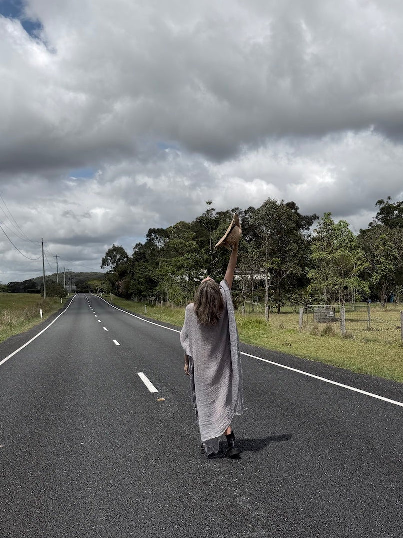 Person in a long estilo emporio maxi dress standing on a road with a cloudy sky