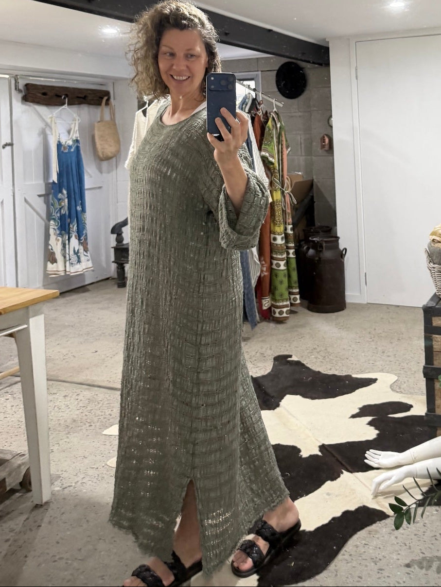 Woman taking a mirror selfie wearing a long green la bottega di brunella linen dress in a room with decor elements.