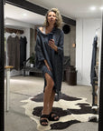 Person standing in a room with a large black-framed mirror, wearing a la bottega di brunella linen dress.