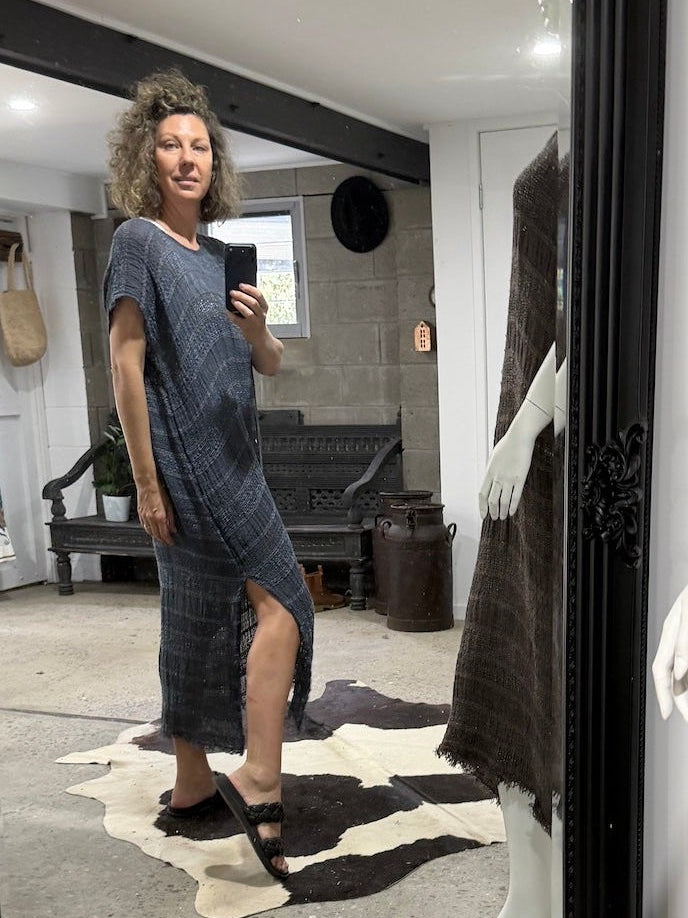 Person taking a photo of themselves in a large mirror with a black frame, wearing a la bottega di brunella linen dress 