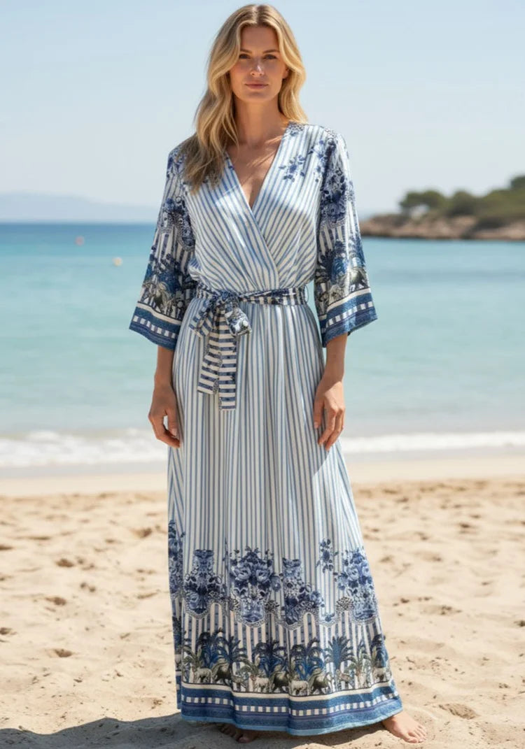 Maxi dress: Miss Goodlife Blue Spirit wrap-neck dress with 3/4 sleeves and tie belt. worn by model in lifestyle shot at the beach LUXAMORE  